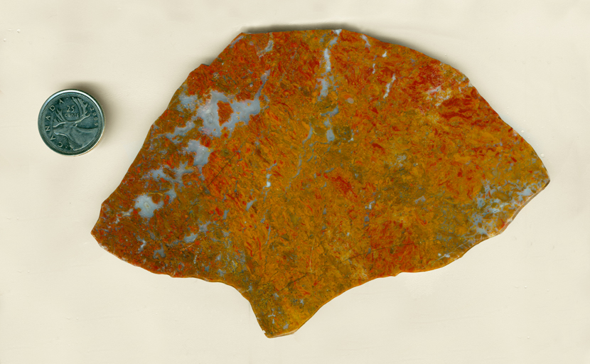 A slab of Roostertail Agate from Durango, Mexico, red, orange and yellow with bright blue rivers and lakes flowing through it.