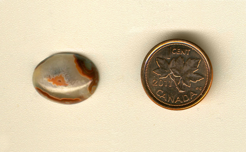 Calibrated oval polished Fairburn Agate cabochon from Nebraska or South Dakota, with three sides of reddish-brown, bordering a white triangular space, within which is a triangular orange island.