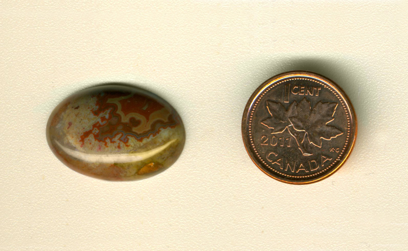 Calibrated oval polished Fairburn Agate cabochon from Nebraska or South Dakota, with a red and yellow fortification pattern flaming downward in a brown and gray sky.