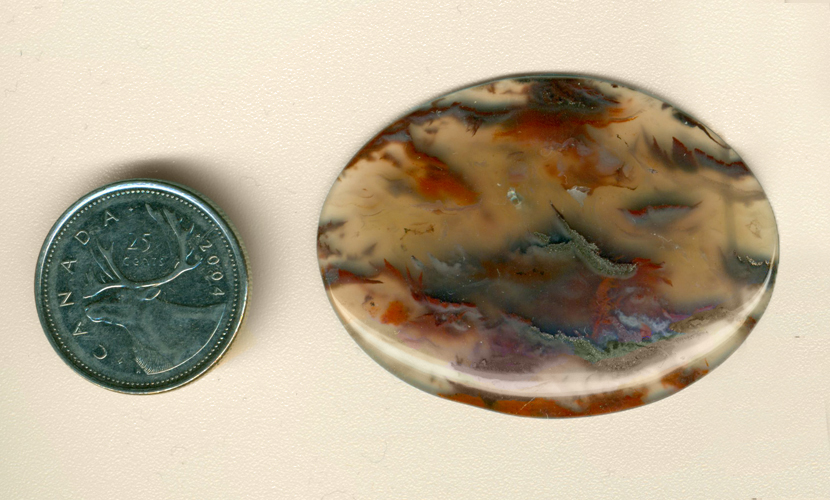 Calibrated oval polished Flame Agate cabochon from Mexico, clear and scattered with red and black flame patterns, which give off small amounts of smoke.