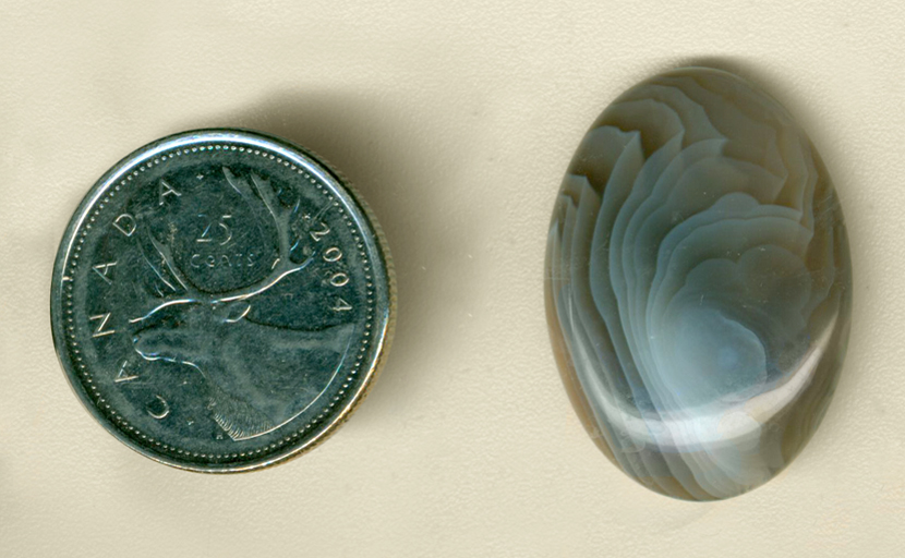 Calibrated oval polished Botswana Agate cabochon, with swirls of blue and gray folded over on themselves.