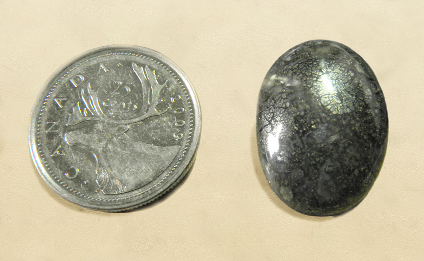 Polished cabochon of agate, full of silvery metallic marcasite inclusions.