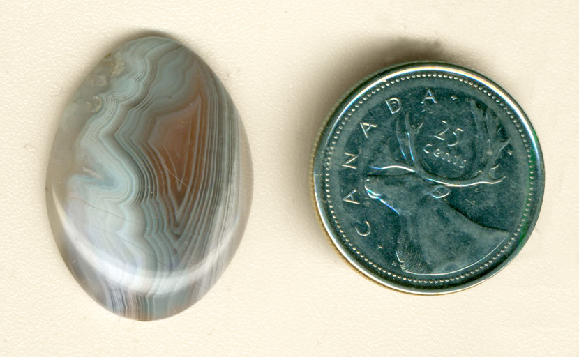 Blue, white and orange pointy fortification shapes, suspended in a clear Botswana Agate cabochon.