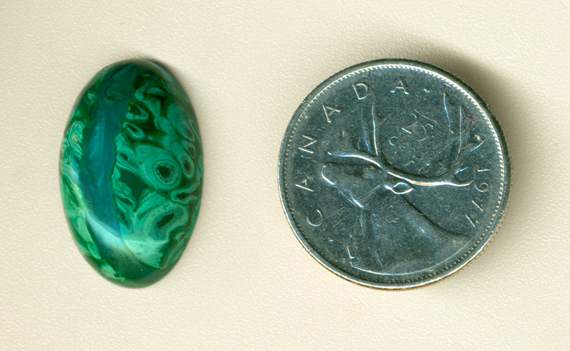 Bright green tubes and a blue line in a cabochon of Malachite in Gem Silica from the Inspiration Mine, Globe County, Arizona.