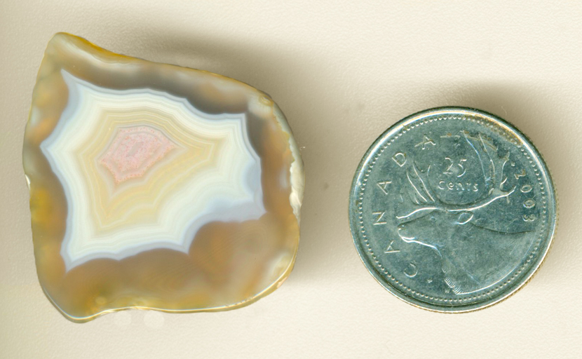 An island of pink, white and yellow fortifications floating far above a golden surface in a Moctezuma Agate.