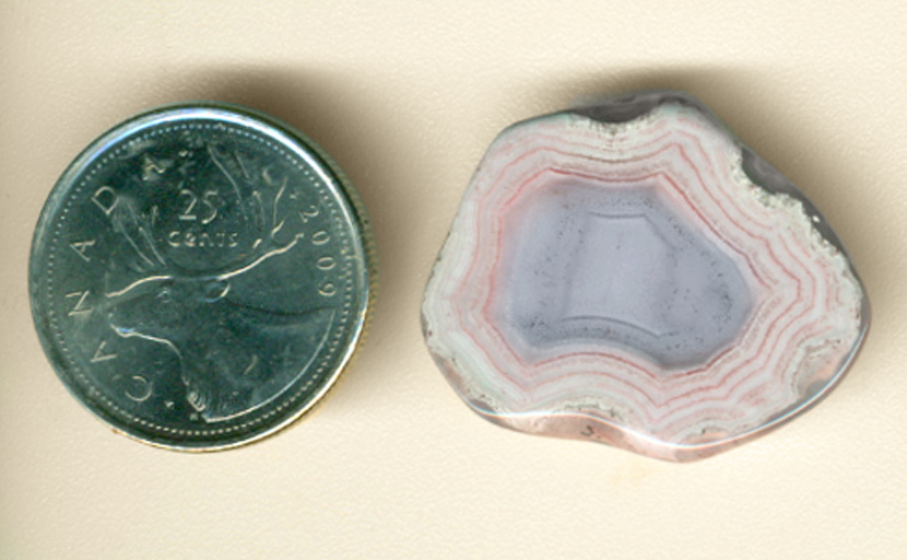 Pink and white lines radiating from a baby-blue core in a polished freeform Parcelas Agate from Mexico.