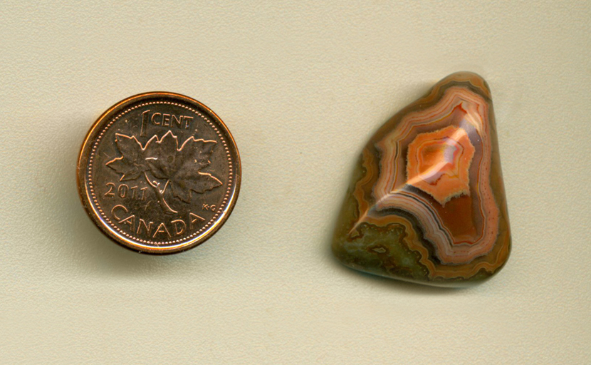 Freeform polished Fairburn Agate cabochon from Nebraska or South Dakota, with a bold orange and yellow fortification pattern, with shadows in between.