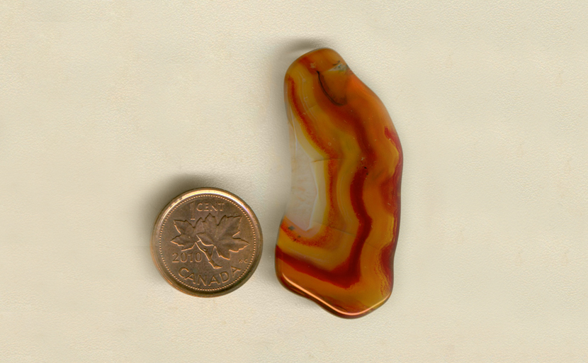 Freeform polished Laguna Agate from Mexico, with a half pattern of orange, yellow and russet brown rippling colors.