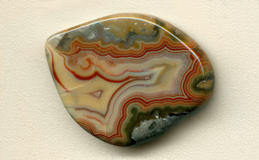 A freeform Fairburn Agate, with a concentric red fortification pattern, surrounded by green orbed patterns.