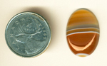 Orange and coffee colors separated by horizontal white lines in a cabochon of Uruguay Agate.
