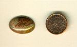 Calibrated oval polished Fairburn Agate cabochon from Nebraska or South Dakota, with a red and yellow fortification pattern flaming downward in a brown and gray sky.