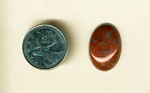 Cabochon with red flowers on a deep blue surface, the shadows between giving it a 3D effect.