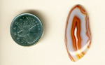 Freeform polished Malawi Agate cabochon, with orange and red layers around and inside a bluish-gray body.