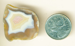 An island of pink, white and yellow fortifications floating far above a golden surface in a Moctezuma Agate.