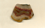 A freeform Coyamito Agate from Mexico, with a central band of yellow fortifications, which, in turn, is covered with flame red and purple flame patterns.