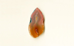 A freeform Coyamito Agate from Mexico, shaped like a candle flame, with orange toward the bottom, fading to pink toward the top, highlighted by blue.