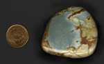 A freeform polished cabochon of Owyhee Picture Jasper from Idaho or Oregon, with a slate blue sky and brown and yellow ground on three sides.