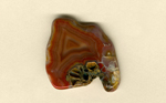 A freeform Coyamito Agate from Mexico, with an orange and red triangular fortification pattern dominating it, resting on the beginnings of an agate pseudomorph after aragonite. 
