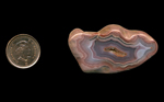 A polished freeform Fortification Agate from Mexico, with successive layers of blue, pink and purple in a deep fortification pattern.