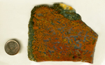 A slab of jasper packed with red and orange coral patterns, surrounded on two edges with green and yellow.