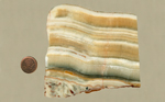 Onyx slab with honey-colored and white stripes, arranged on top of a darker stripe and reddish patterns underneath it.