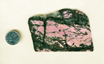 A slab of Rhodonite from Rosemund, California, with a strong pink background and glittering black lines and patches in the foreground.